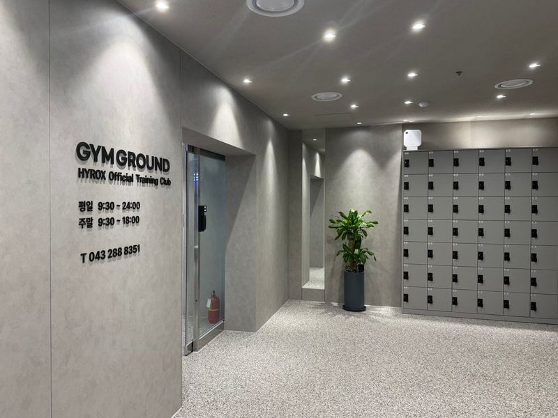 GYM GROUND 로고와 운영시간이 있는 입구, 짐 보관함